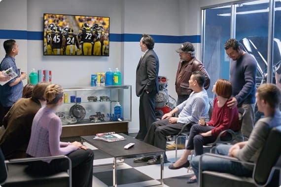 Auto shop waiting area with people watching sports on TV