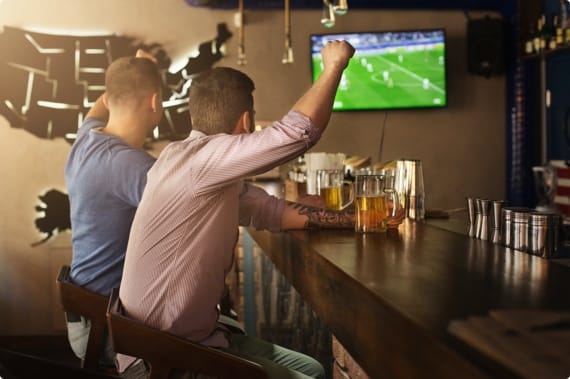 Two men cheering at while watching sports at sports bar