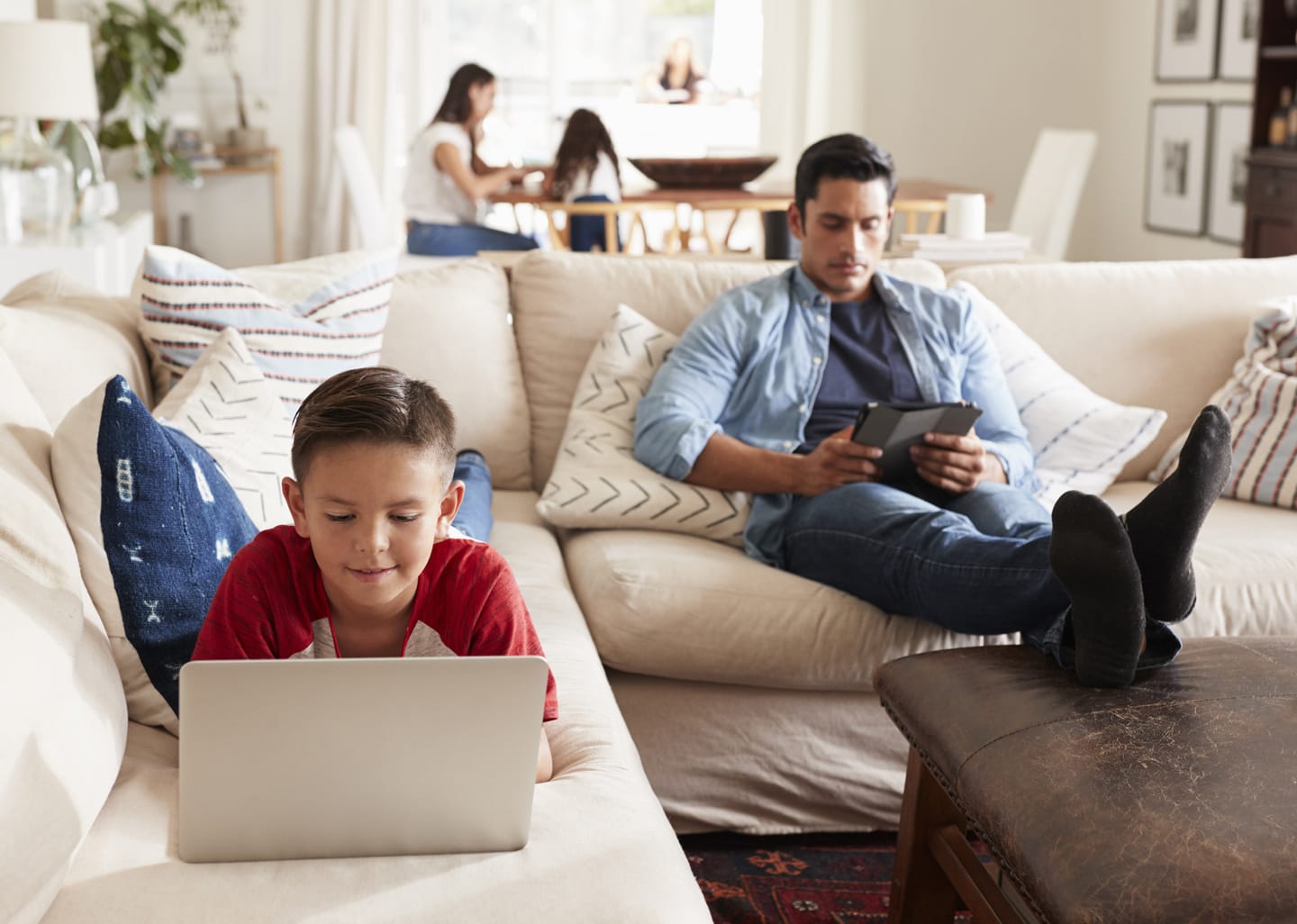 a father and son using their tablets on the couch