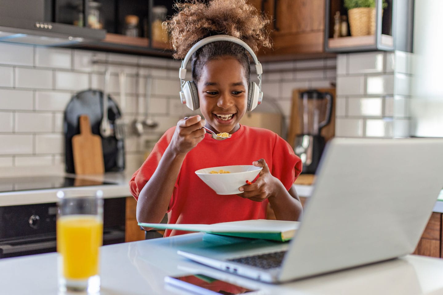 A girl eating cereal while using a laptop