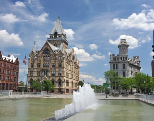 Exterior shot of buildings and a fountain. 