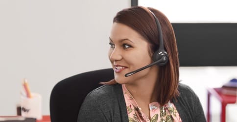 A woman speaks to a customer through a headset.