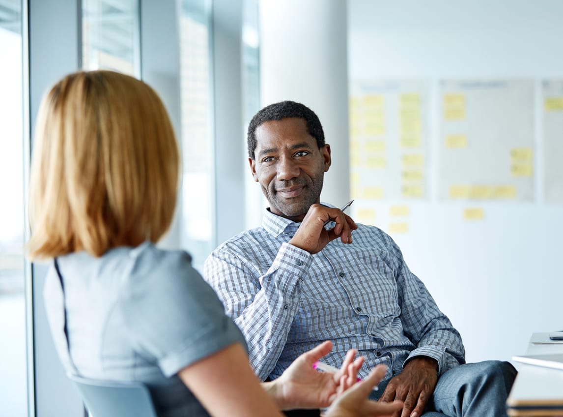 A man and a woman speak to each other in an office