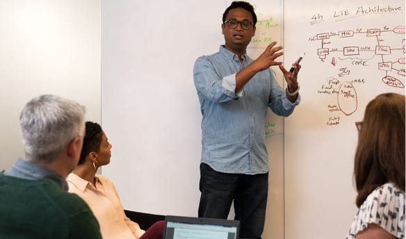 A man presents a chart to several coworkers during a meeting. 