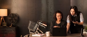 A woman shows her colleague her computer screen.