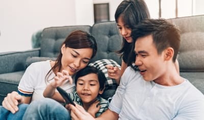 Family on couch playing game on phone