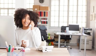 Kobieta rozmawia na telefonie stacjonarnym w pracy