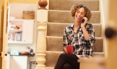 Mulher sentada na escada falando no telefone dela