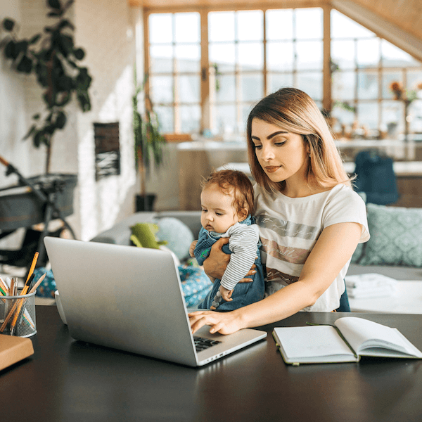 lady holding baby while using computer