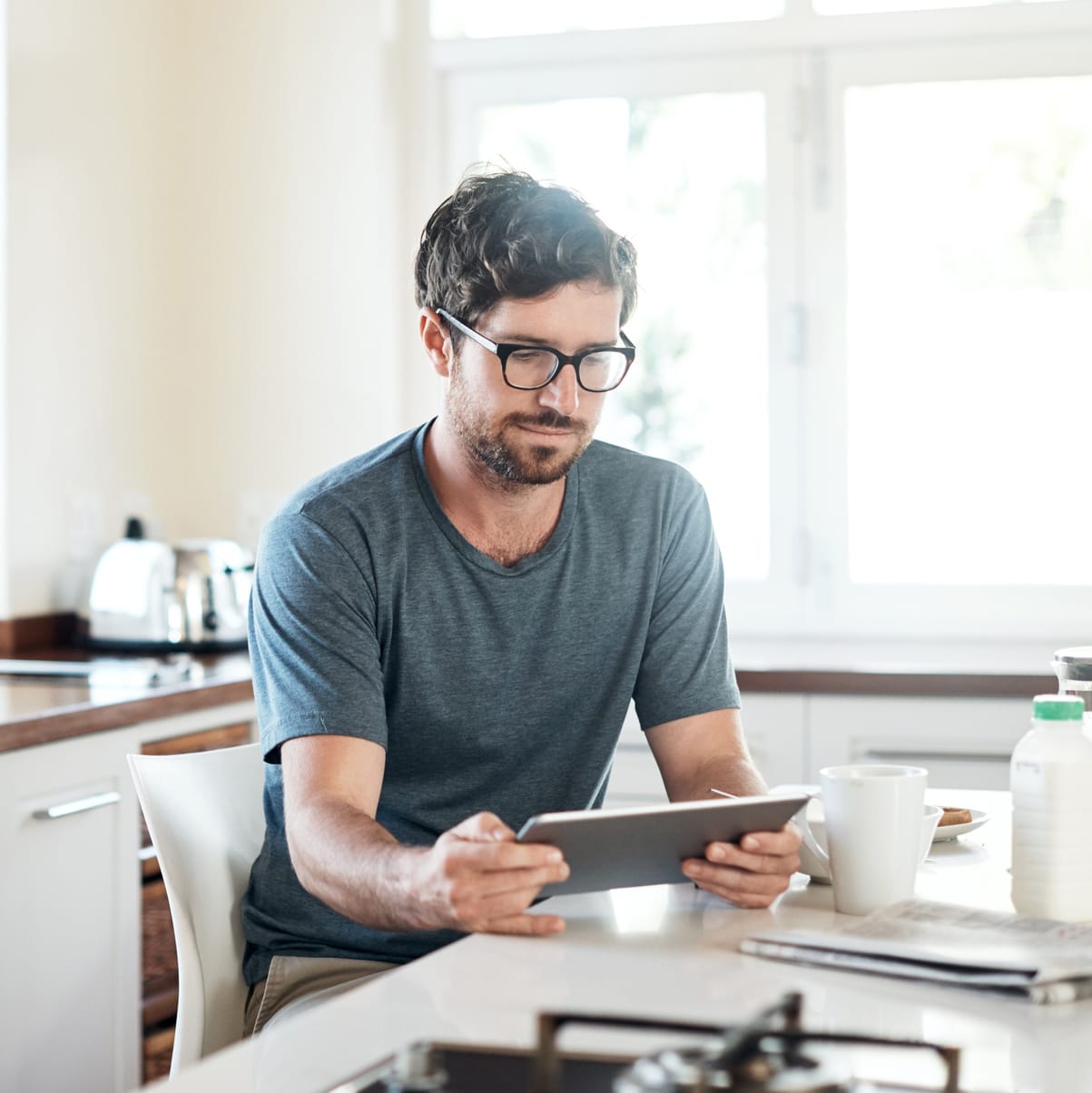 man using tablet at kitchen table