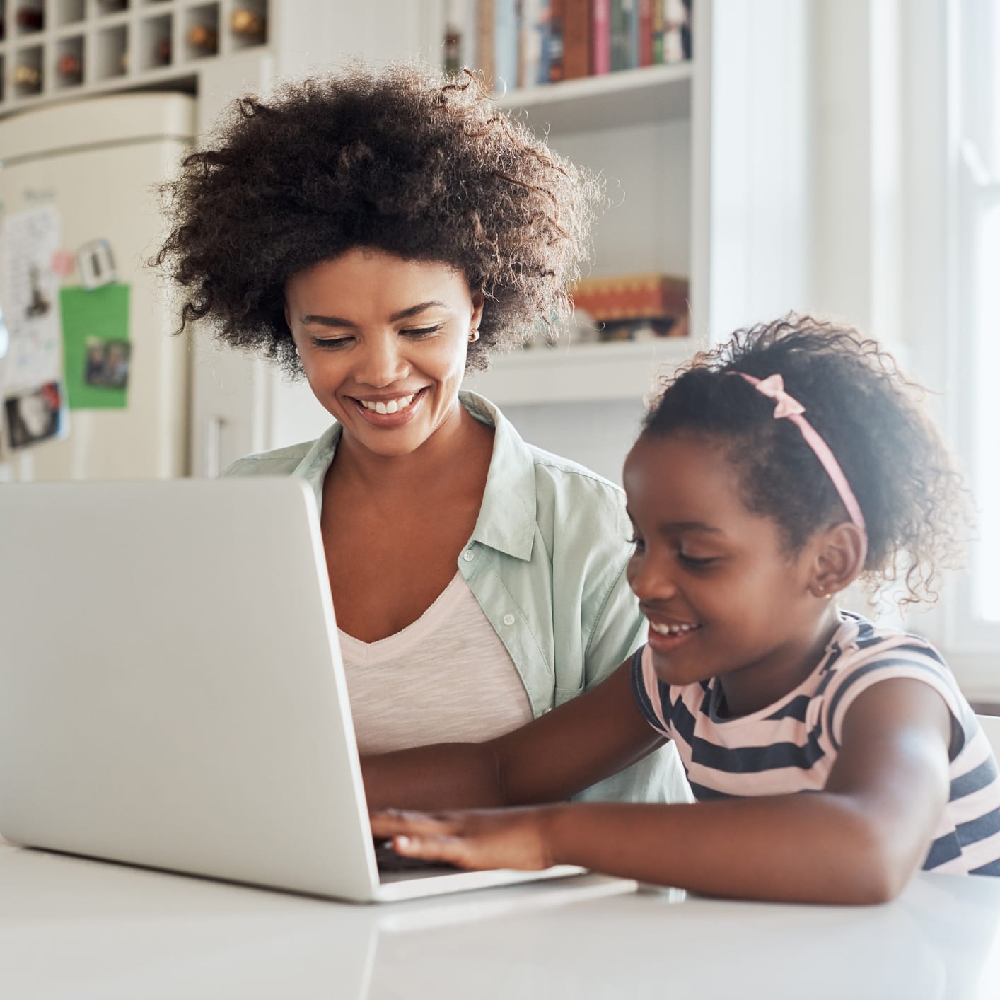 Mother and daughter using laptop and smiling