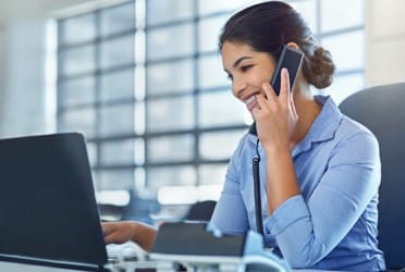 woman uses laptop and landline phone