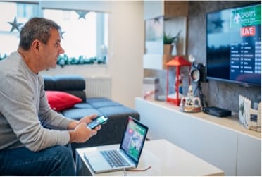 man watching tv and using computer