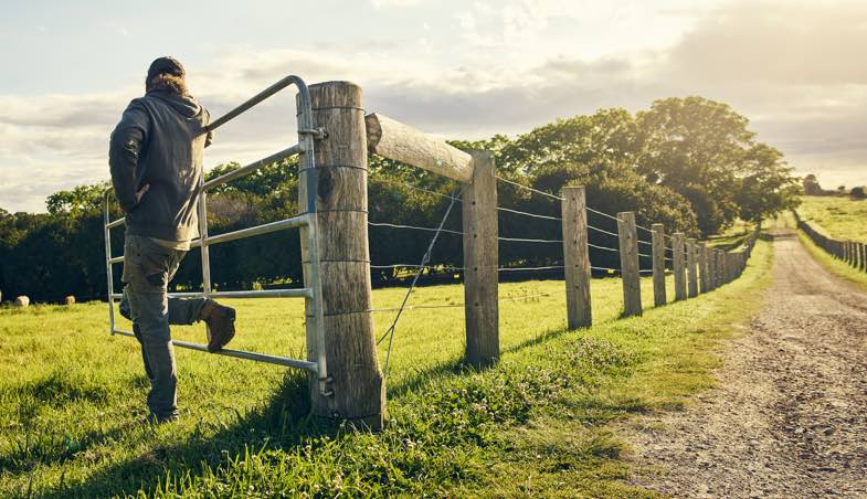 man leaning against open fence gate