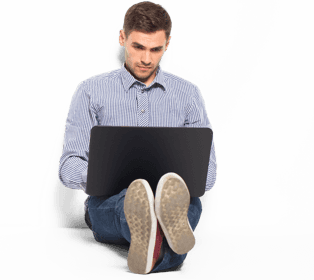 A man in a blue shirt typing on a laptop