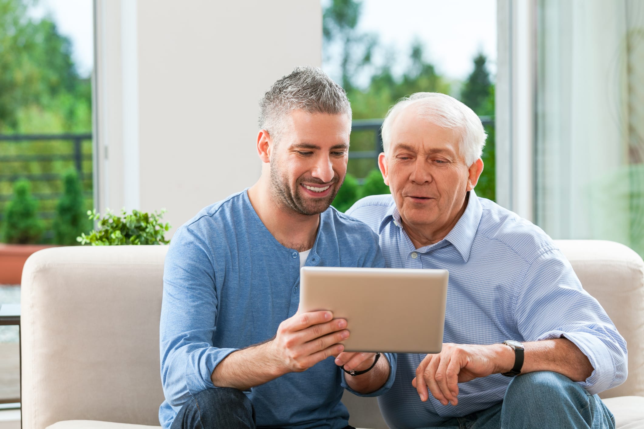 Middle aged man and eldery man look at ipad.