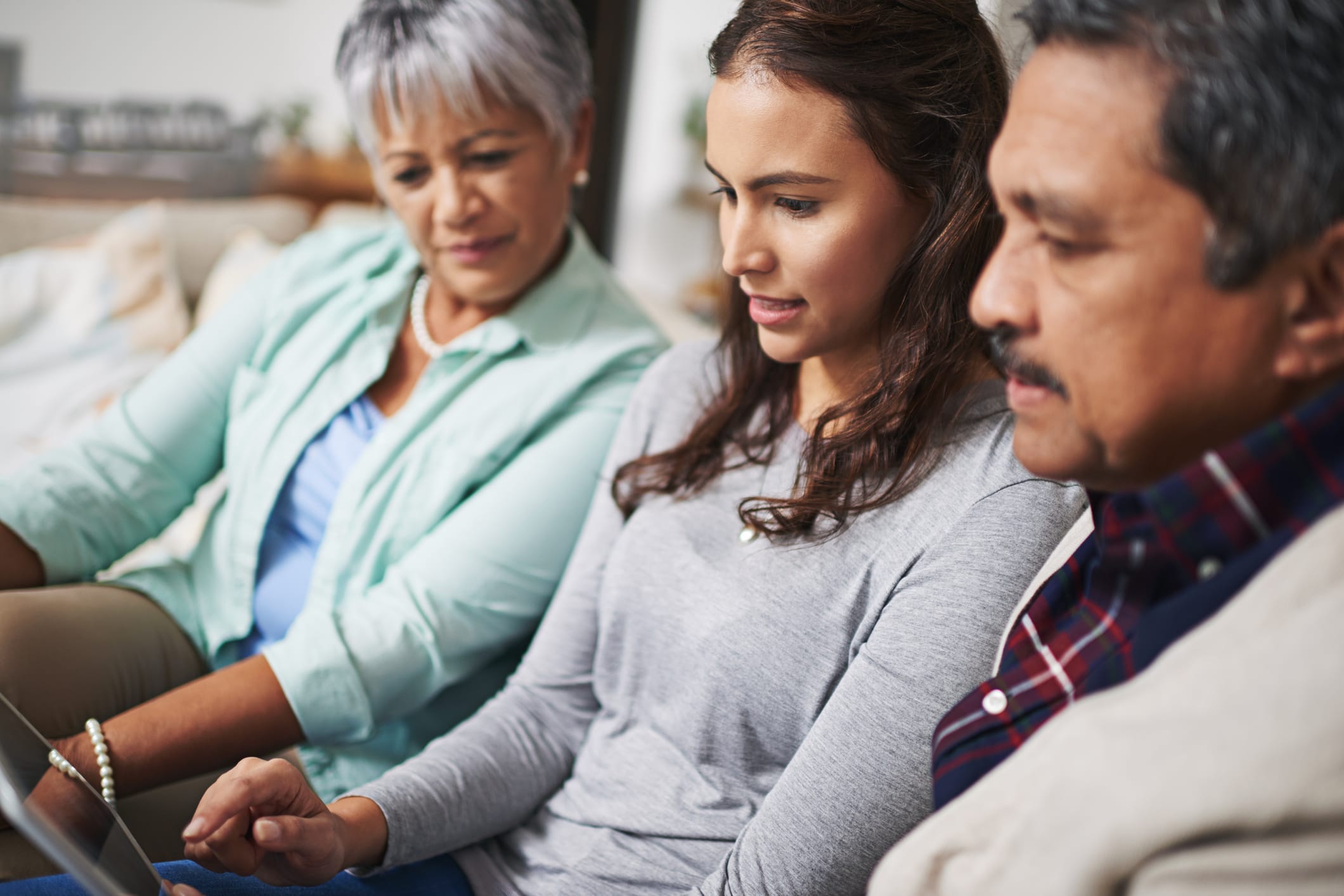 Young woman showing elderly couple a computer.