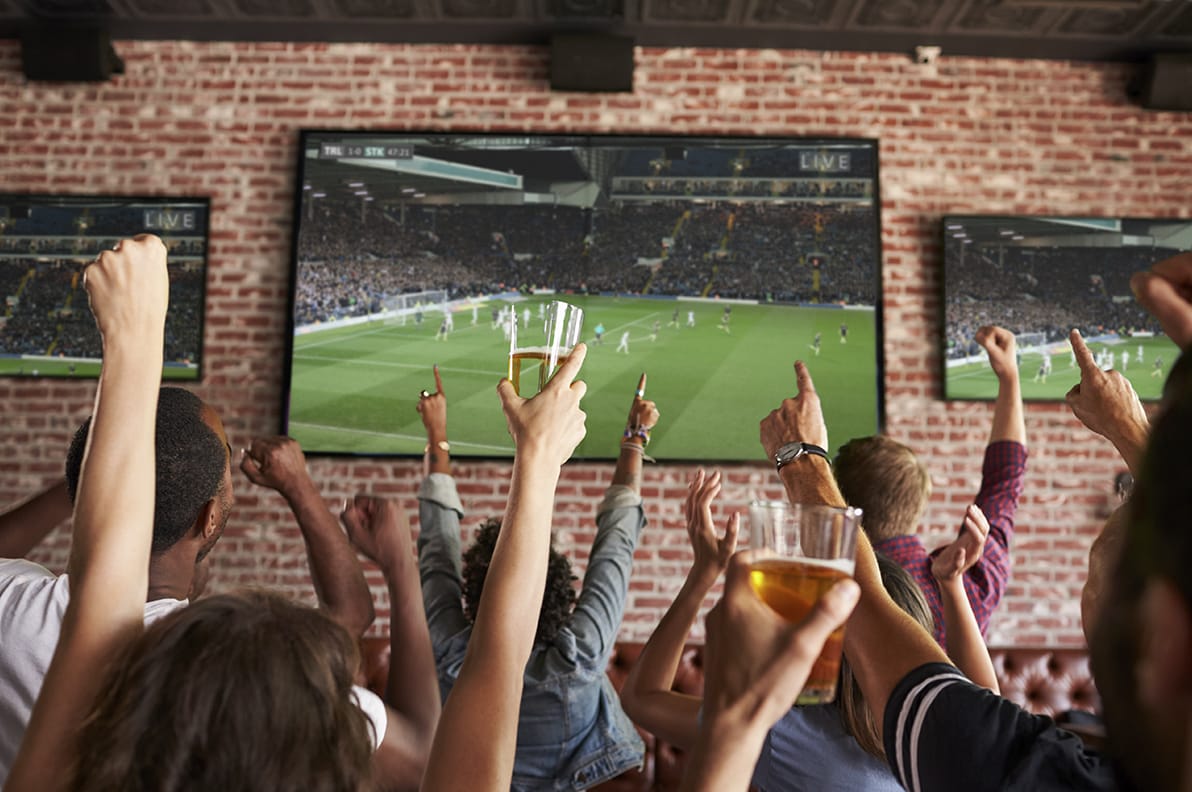 crowd cheering at sports bar while watching soccer match