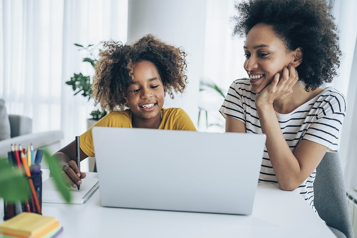 Mother and daughter working together on a laptop and smiling