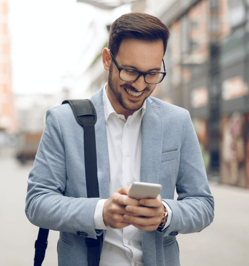 A businessman looking at his smartphone and smiling