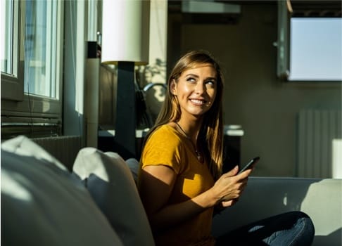 woman looks out window with smile on her face