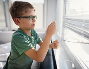 child opening window blinds
